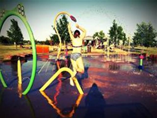 A woman joyfully splashes in a water park